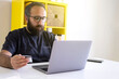 © Designerant - Holding credit card, young Caucasian millennial worker holding credit card and spending money online. Bearded young hipster shopping online.