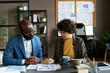 © pressmaster - Businesswoman discussing financial graphs on papers with her partner at table during meeting