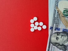 American One Hundred Dollar Bills And Pills On Red Background