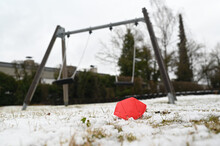 FFP2 Mask Lying On Snow-covered Ground With A Swing In The Background