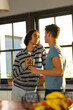 © Wavebreak Media - Diverse gay male couple holding coffee cups looking at each other in the kitchen at home
