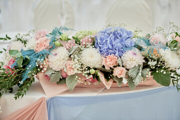 Lush floral arrangement on wedding table in restaurant, copy space. Luxury wedding decorations. Banquet table for newlyweds with white, pink and blue flowers.