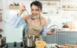 © NaMong Productions - Happy beautiful young asian woman cooking soup and smell soup in kitchen room.