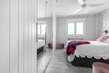 Fototapeta  - Bedroom with built-in wall-to-wall wardrobe with mirror and wooden doors, double bed with cushions and upholstered headboard and wall with decorative paper