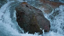 A Strong Mountain Water Stream Flowing Around Big Boulder. Slow Motion. 
