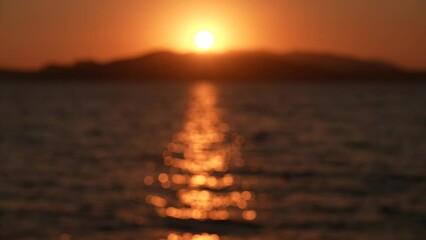 Wall Mural - beautiful blurry sunset seascape. defocused silhouettes of dark mountains on horizon, sun circle iso