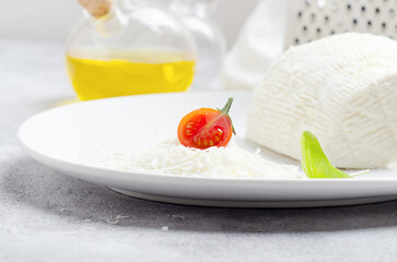 Salted ricotta on white plate with basil.  Selective focus.