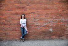 Smiling Girl Leaning Against Red Brick Wall