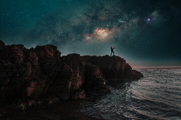 Wall Mural - silhouette of a saxophonist playing on a cliff at night with the milky way in the background