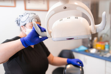 Female dentist preparing dental chair light