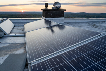 Wall Mural - Solar panels located on the roof of the block. Green energy in modern city.  Sunset in the background