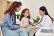 © Studio Romantic - Pediatric medical examination. Friendly female doctor or nurse listens to lungs, heartbeat and breathing of cute little girl. Joyful mother and daughter at medical examination at children's hospital.