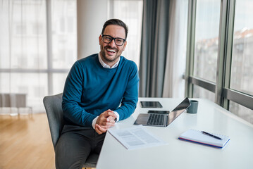 Wall Mural - portrait of happy businessman with laptop and document at office desk