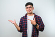 © Reza - Young handsome asian man pointing with hand finger to the side looking at the camera.