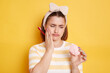 © sementsova321 - Portrait of sad sick Caucasian woman wearing t shirt and hair band, holding marshmallow and toothbrush, having dental problems after drinking sweets, posing isolated on yellow background.