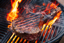 Barbecue Dry Aged Wagyu Tomahawk Steak Offered As Close-up On A Charcoal Grill With Fire And Smoke