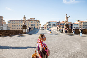 Canvas Print - Young stylish woman walking near Holy Trinity bridge in Florence city, visiting famous italian landmarks. Idea of italian style and travel