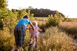 © Maryna - brother teaches little sister to ride bicycle. girl rides along rural road on two-wheeled bicycle among summer grasses