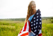 Young Woman With American USA Flag  On Blooming Meadow. Independence Day, 4th July.