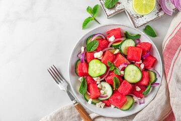 Wall Mural - Summer fruit and vegetable salad made of watermelon, cucumber, soft cheese and onion on white table. Top view