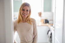 Smiling Young Woman Standing In The Kitchen 
