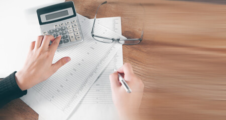 young woman counts on calculator and makes notes on papers