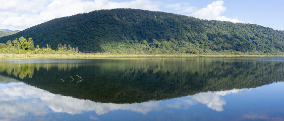 Wall Mural - Stunning reflection of bush-clad mountains in calm surface of Lake Moeraki