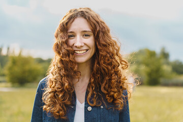 spontaneous pretty young redhead woman smiling looking at the camera outdoors in the nature - portra