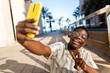 © Daniel - Young black man taking selfie using phone making peace sign. Happy, African american male having fun.
