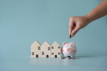 Piggy Bank And Small Wooden House At Back Concept Of Savings. Save Money To Buy , Loan , Rent The House.