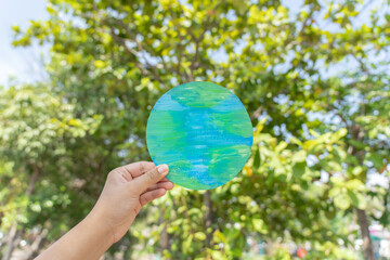 hand holding earth sign up with natural environment sky and tree as background. environment protecti
