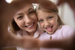 Young cheerful mother and funny little daughter joined their fingers showing hearts symbol on camera, close up happy faces webcam view. Unconditional love, family ties, happy motherhood, fun concept