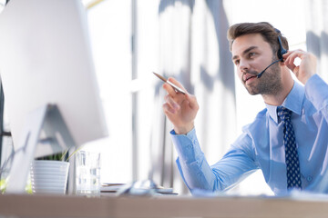 Sticker - Cheerful young support phone male operator in headset, at workplace while using computer