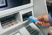 Closeup Of Man Hand Inserting E-card Into ATM Slot