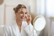 © Prostock-studio - Cheerful beautiful adult lady using moisturizing eye cream