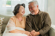 © whyframeshot - old senior asian retired age marry couple wellness lifesstyle together at home,old people laugh smile together with love and bonding on sofa in living room home interior background
