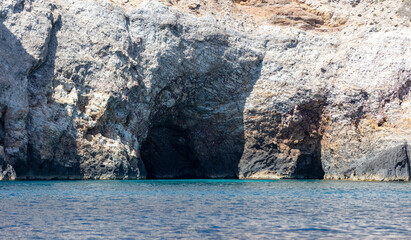 Wall Mural - Cave and cliff, Aegean Sea. Cyclades Greece. Rock coast, turquoise water. Seascape near Ios island