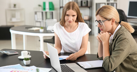 Beautiful businesswoman and her colleague discussing issue at workplace