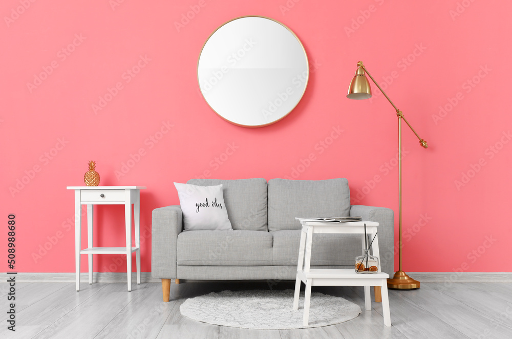 Comfortable sofa and modern lamp near pink wall