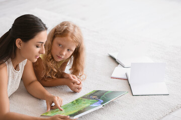 Canvas Print - Little redhead girl reading book with her teacher in classroom