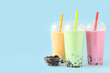 canvas print picture - Plastic cups of different tasty bubble tea on blue background