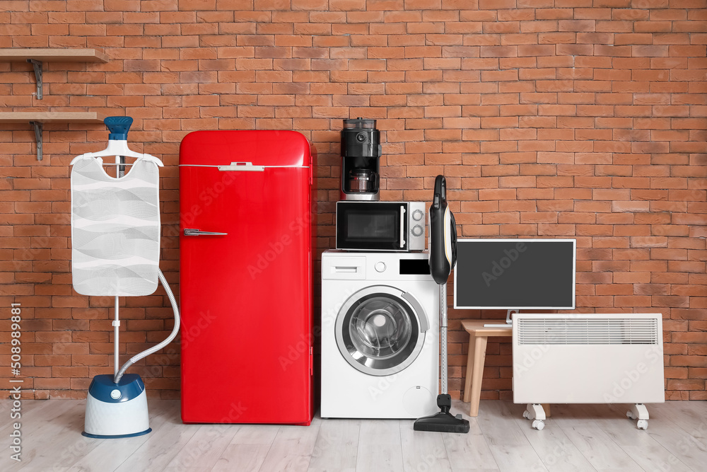 Modern household appliances near brick wall in room