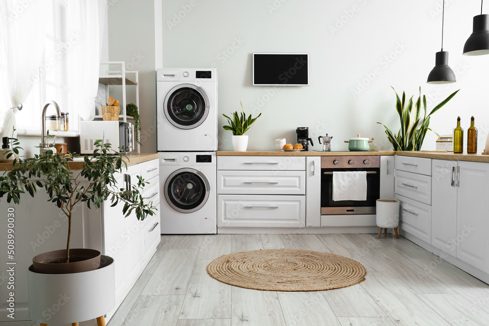 Stylish interior of kitchen with modern washing machines