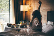 © Mariia Korneeva - Woman eating breakfast in the hotel room. Room service breakfast in hotel room.
