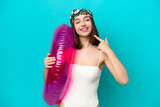 Fototapeta Młodzieżowe - Young Ukrainian woman holding air mattress isolated on blue background giving a thumbs up gesture