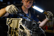 © Dmytro Hai - Blurred workman in gloves holding lamp near damaged car engine in service