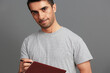 © SHOTPRIME STUDIO - portrait man with a book in his hands in a gray T-shirt emotions Gray background