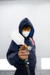 © Dmytro Hai - Blurred repairman in suit and respirator holding pulverizer in auto painting chamber