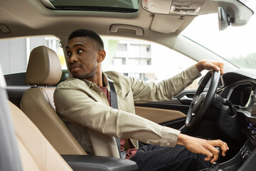 African American male driver looks back and parks the car