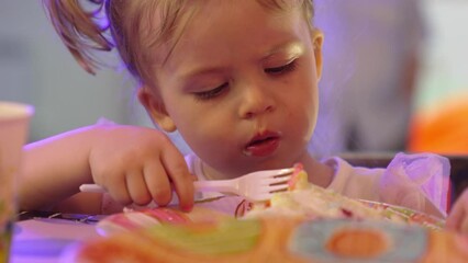 cute little girl eating a piece of cake on a paper plate with a plastic fork.